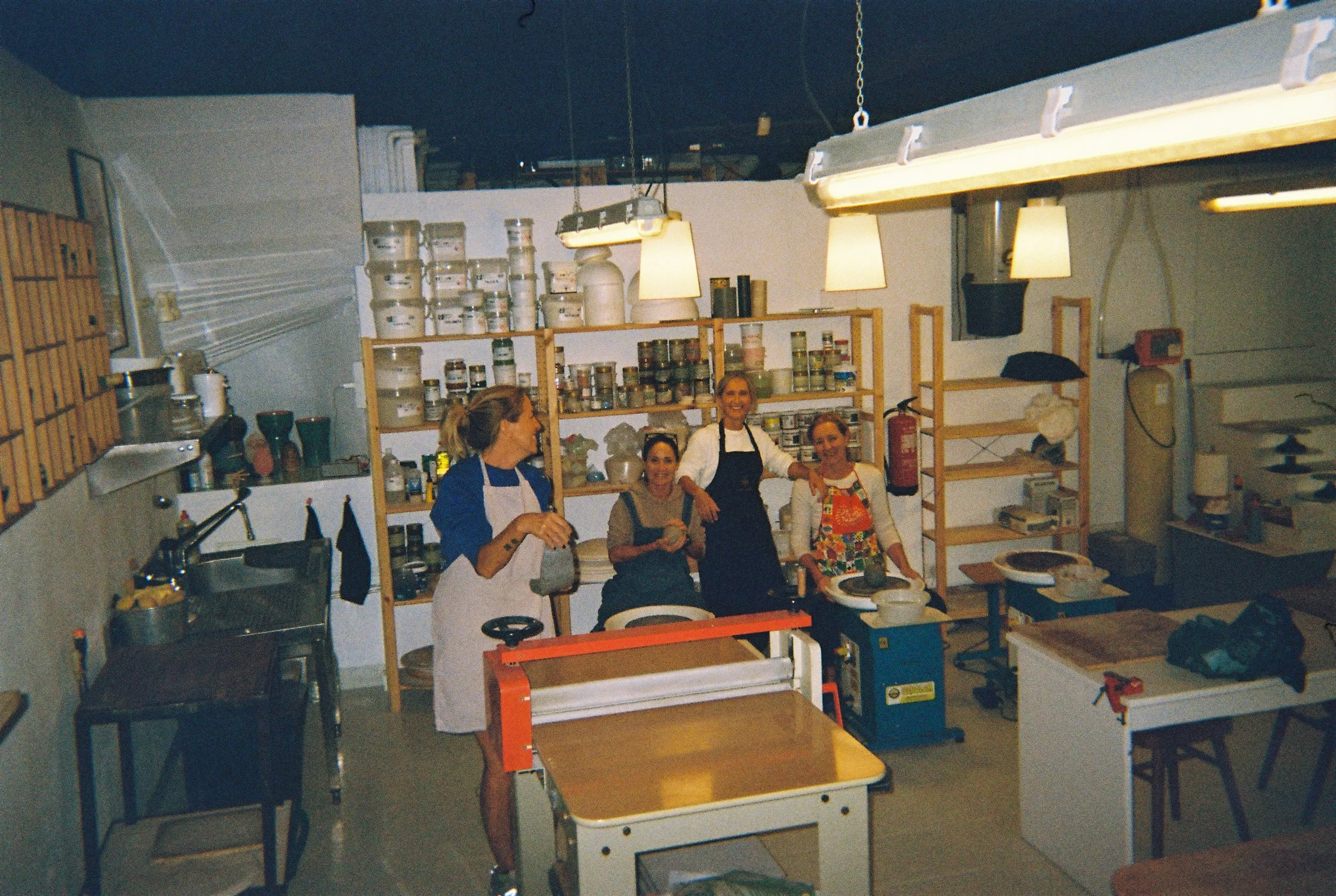 Grupo de alumnas sonriendo entre los tornos y las estanterías de esmaltes durante el taller